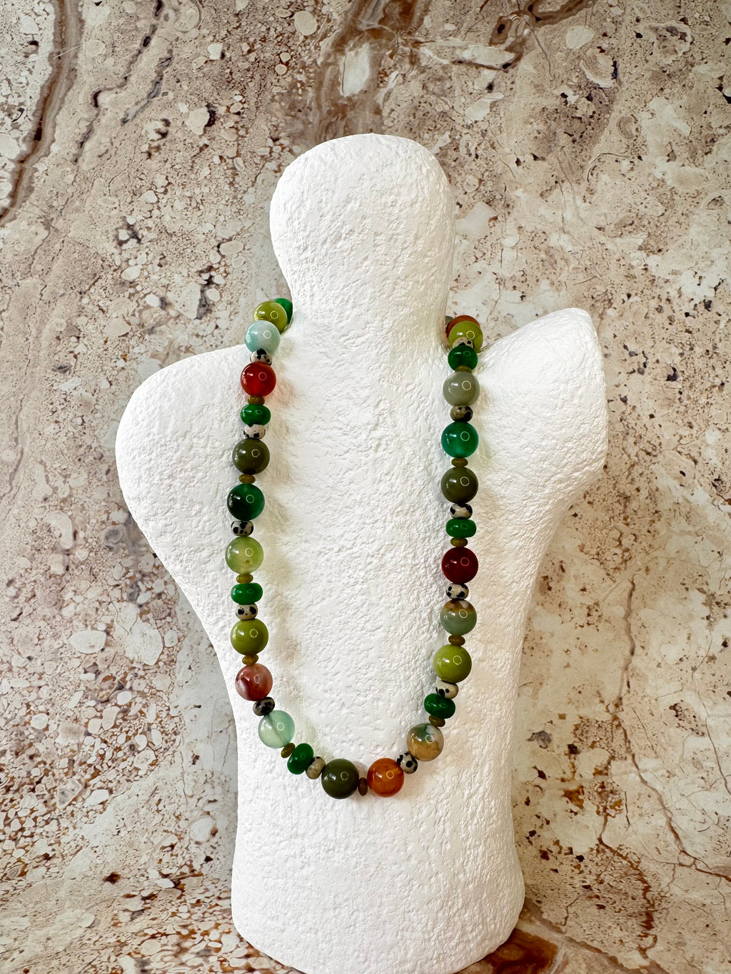 Rachel necklace with coloured flower agate, jade, glass and jasper beads on a white mannequin bust against a neutral marble background